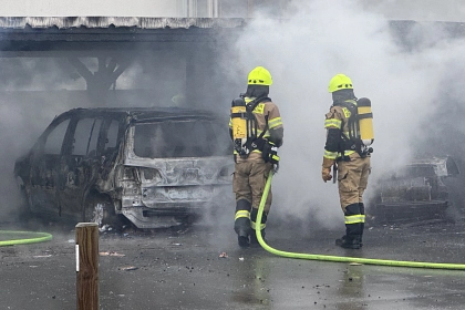 Zwei Feuerwehrleute löschen ein brennendes Auto