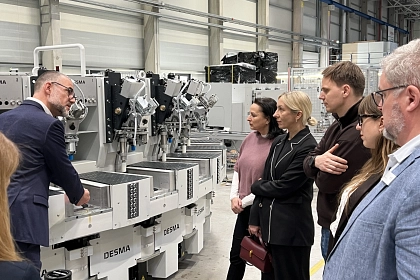 Die Delegation aus Cesis schaut sich die Produktion im Achimer Unternehmen Desma an, wo ihr alles vor einer Schuhmaschine erklärt wird.